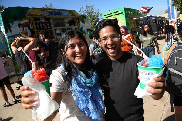 two students at an event holding shaved ice