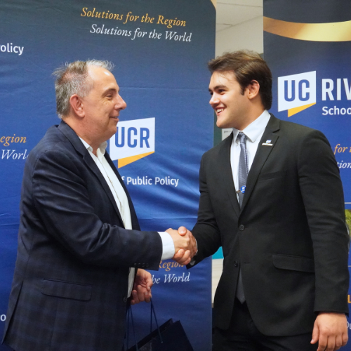 A student shaking the hand of a policy professional.