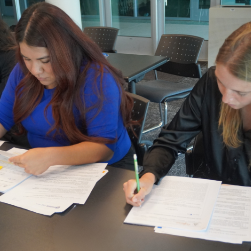 Two female students writing on paper.