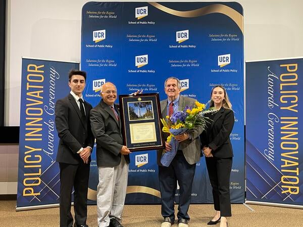 Dean Anil Deolalikar with students presenting the Policy Innovator Award to Randall Lewis