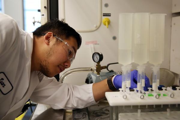 Twan Nguyen checks a machine testing surface water for PFAS compounds at the Orange County Water District. (Dania Maxwell / Los Angeles Times)