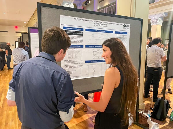 A presenter in front of her presentation board speaking to a guest